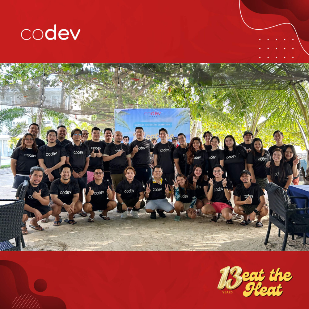 CoDev employees in Davao pose for an anniversary group photo in a garden area.